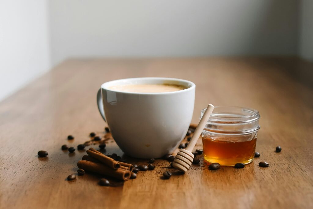 Warm chai with honey and cinnamon sticks on a wooden table, offering a cozy vibe.