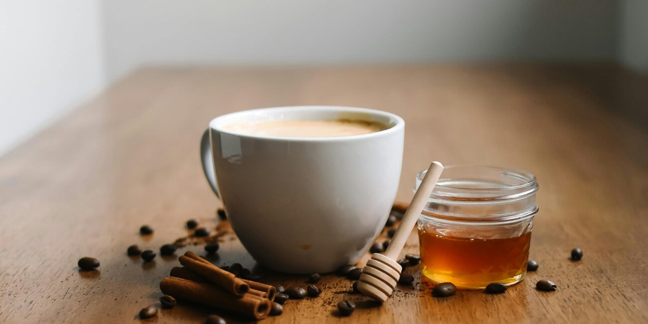 Warm chai with honey and cinnamon sticks on a wooden table, offering a cozy vibe.